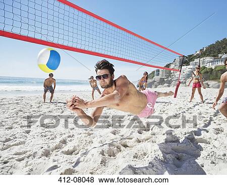 Stock Photo - Man diving for volleyball on beach. Fotosearch