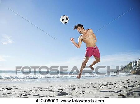 Man in swim trunks heading soccer ball on beach View Large Photo Image Stock Image - Man in swim trunks heading soccer ball on beach. Fotosearch