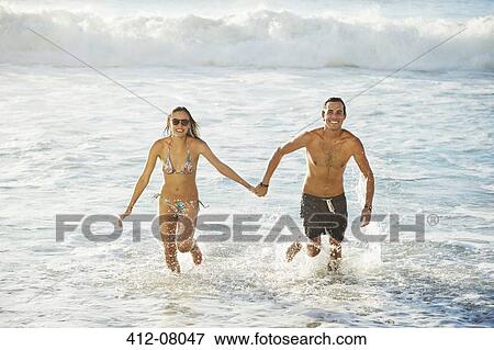 Portrait of happy couple holding hands and running in ocean View Large Photo Image Stock Photo - Portrait of happy couple holding hands and running in ocean. Fotosearch