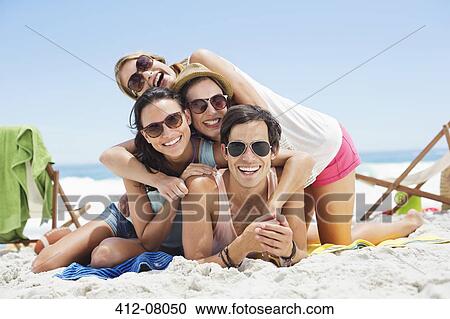 Portrait of happy friends laying on top of each other on beach View Large Photo Image Stock Image - Portrait of happy friends laying on top of each other on beach. Fotosearch