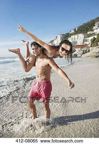 Portrait of happy man lifting woman on beach View Large Photo Image Stock Photography - Portrait of happy man lifting woman on beach. Fotosearch