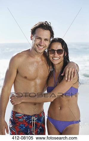 Stock Photography - Portrait of smiling couple hugging on beach. Fotosearch