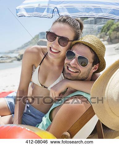 Portrait of smiling couple wearing sunglasses on beach View Large Photo Image Stock Photograph - Portrait of smiling couple wearing sunglasses on beach. Fotosearch