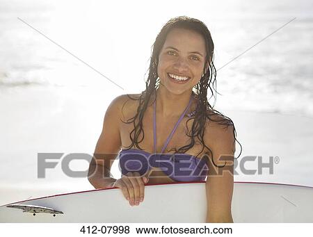 Portrait of smiling woman holding surfboard on beach View Large Photo Image Stock Photo - Portrait of smiling woman holding surfboard on beach. Fotosearch