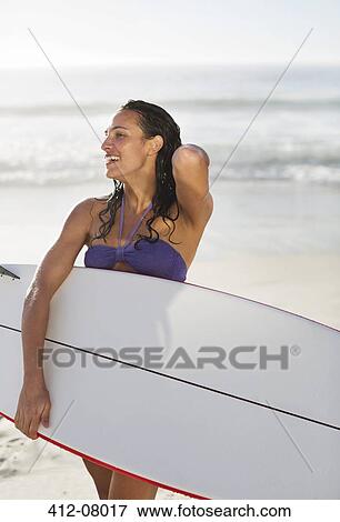 Smiling woman holding surfboard on beach View Large Photo Image Stock Photo - Smiling woman holding surfboard on beach. Fotosearch