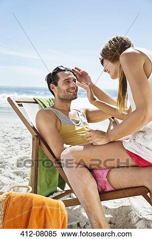 Woman applying sunscreen to man's nose at beach View Large Photo Image Stock Photography - Woman applying sunscreen to man's nose at beach. Fotosearch