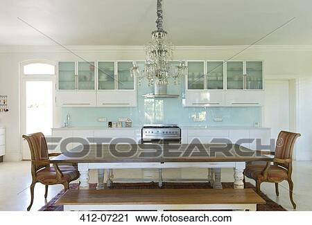 Stock Image - Chandelier over wooden table in kitchen. Fotosearch