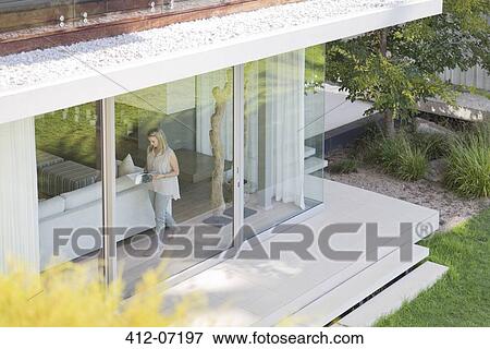 Woman walking along window inside house View Large Photo Image Stock Photo - Woman walking along window inside house. Fotosearch