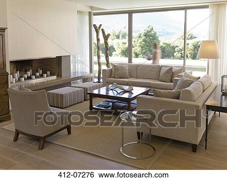 Woman walking at window of living room View Large Photo Image Stock Photograph - Woman walking at window of living room. Fotosearch