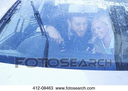 Business people text messaging with cell phone inside car View Large Photo Image Stock Image - Business people text messaging with cell phone inside car. Fotosearch