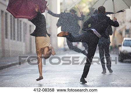 Stock Photo - Business people with umbrellas dancing in rain. Fotosearch
