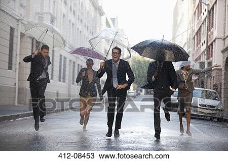 Business people with umbrellas running in rainy street View Large Photo Image Stock Image - Business people with umbrellas running in rainy street. Fotosearch