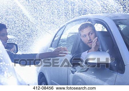 Stock Photograph - Businessman in car providing directions to woman in rain. Fotosearch