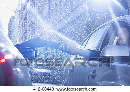 Stock Photo - Businessman in car reaching for paperwork in rain. Fotosearch