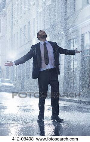 Businessman standing with arms outstretched in rainy street View Large Photo Image Stock Photo - Businessman standing with arms outstretched in rainy street. Fotosearch