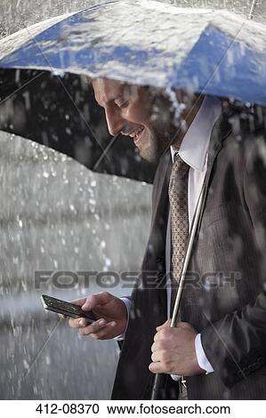 Businessman text messaging on cell phone under umbrella in rain View Large Photo Image Stock Image - Businessman text messaging on cell phone under umbrella in rain. Fotosearch