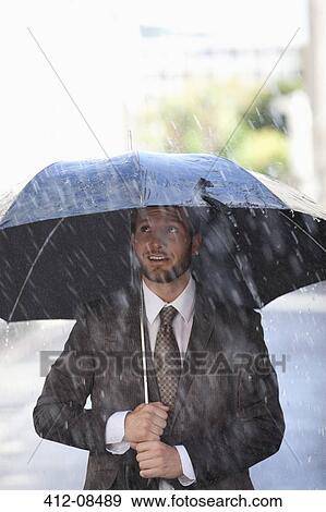Stock Photo - Businessman under umbrella in rain. Fotosearch
