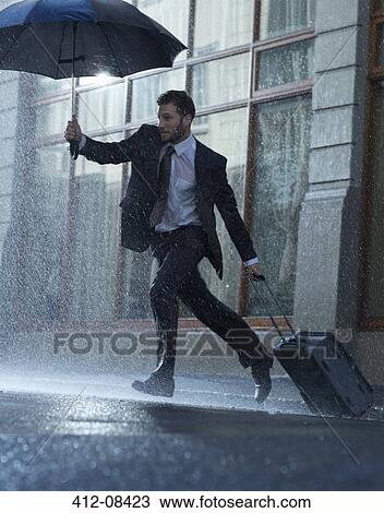 Businessman with suitcase and umbrella crossing rainy street View Large Photo Image Stock Image - Businessman with suitcase and umbrella crossing rainy street. Fotosearch