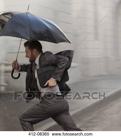 Stock Photography - Businessman with umbrella running in rain. Fotosearch