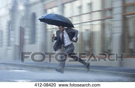 Businessman with umbrella running across rainy street View Large Photo Image Stock Image - Businessman with umbrella running across rainy street. Fotosearch