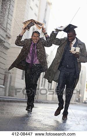 Businessmen with coffee covering heads with newspaper in rainy street View Large Photo Image Stock Photo - Businessmen with coffee covering heads with newspaper in rainy street. Fotosearch