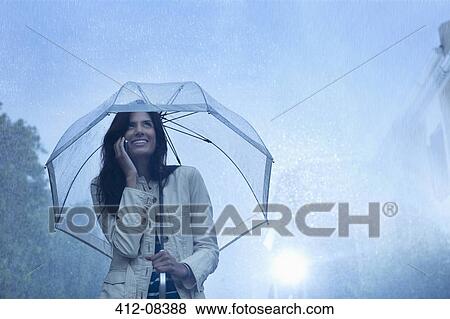 Businesswoman talking on cell phone under umbrella in rain View Large Photo Image Stock Photo - Businesswoman talking on cell phone under umbrella in rain. Fotosearch
