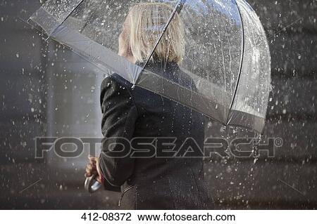 Stock Image - Businesswoman under umbrella in rain. Fotosearch