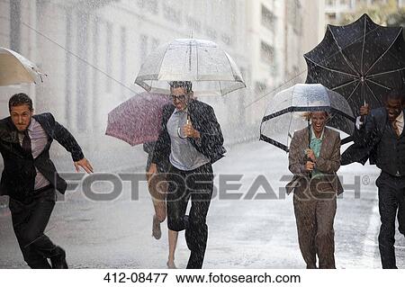 Stock Photo - Enthusiastic business people with umbrellas running in rainy street. Fotosearch