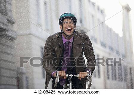 Enthusiastic businessman riding bicycle in rain View Large Photo Image Stock Photography - Enthusiastic businessman riding bicycle in rain. Fotosearch
