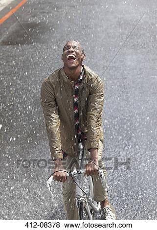 Enthusiastic man riding bicycle in rain View Large Photo Image Stock Photo - Enthusiastic man riding bicycle in rain. Fotosearch