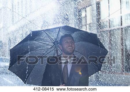 Happy businessman under umbrella in rain View Large Photo Image Stock Photography - Happy businessman under umbrella in rain. Fotosearch