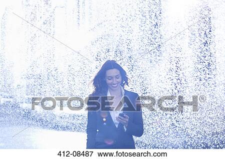 Happy businesswoman text messaging with cell phone in rain View Large Photo Image Stock Photo - Happy businesswoman text messaging with cell phone in rain. Fotosearch