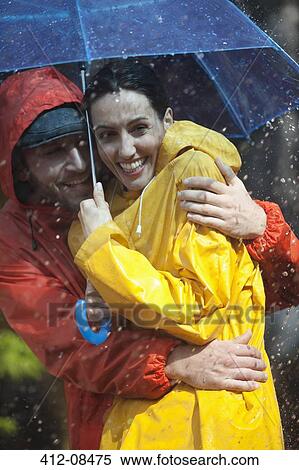 Happy couple hugging under umbrella in rain View Large Photo Image Stock Photography - Happy couple hugging under umbrella in rain. Fotosearch