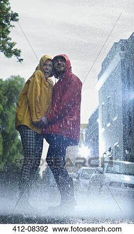 Happy couple in raincoats holding hands in rain View Large Photo Image Stock Image - Happy couple in raincoats holding hands in rain. Fotosearch