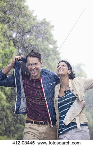 Stock Photography - Happy couple walking in rain. Fotosearch