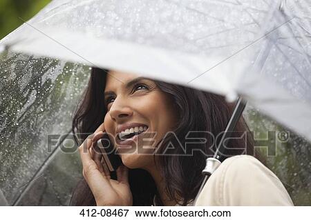 Happy woman talking on cell phone under umbrella in rain View Large Photo Image Stock Photo - Happy woman talking on cell phone under umbrella in rain. Fotosearch