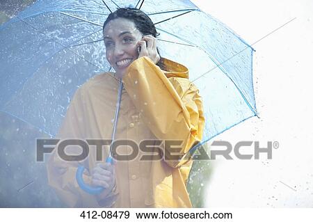 Happy woman talking on cell phone under umbrella in rain View Large Photo Image Stock Photo - Happy woman talking on cell phone under umbrella in rain. Fotosearch