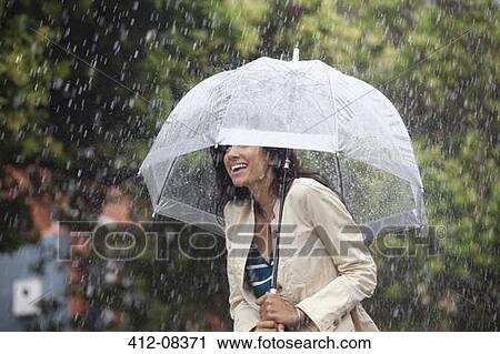 Stock Image - Happy woman under umbrella in rain. Fotosearch