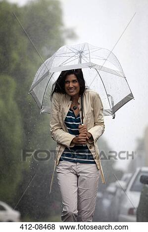 Stock Photo - Happy woman under umbrella in rain. Fotosearch