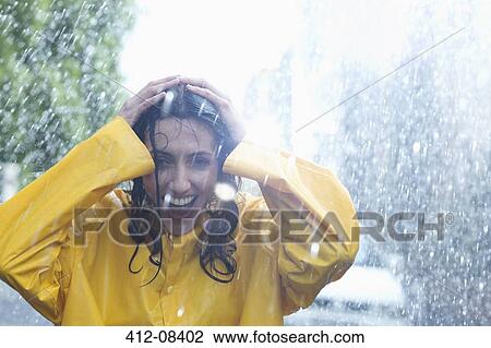 Stock Image - Happy woman with hands on head in rain. Fotosearch
