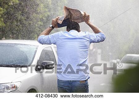 Man covering head with newspaper in rainy street View Large Photo Image Stock Image - Man covering head with newspaper in rainy street. Fotosearch
