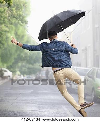 Picture - Man dancing with umbrella in rainy street. Fotosearch
