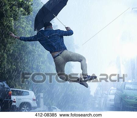 Stock Photography - Man with umbrella jumping in rain. Fotosearch