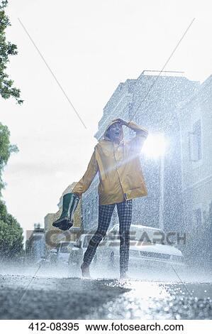 Woman in raincoat carrying wellingtons and walking barefoot in rain View Large Photo Image Stock Photography - Woman in raincoat carrying wellingtons and walking barefoot in rain. Fotosearch