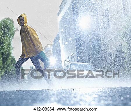 Picture - Woman walking barefoot on rainy street. Fotosearch