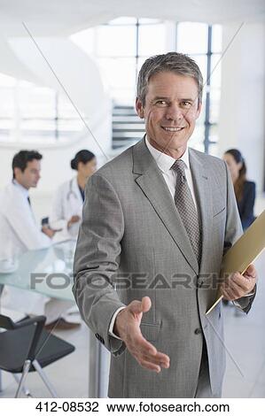 Businessman offering handshake in meeting View Large Photo Image Stock Image - Businessman offering handshake in meeting. Fotosearch