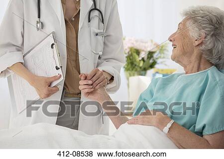 Doctor and aging patient holding hands in hospital View Large Photo Image Stock Photo - Doctor and aging patient holding hands in hospital. Fotosearch