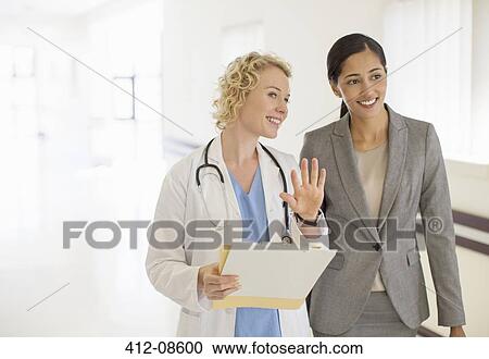 Doctor and businesswoman talking in hospital corridor View Large Photo Image Stock Image - Doctor and businesswoman talking in hospital corridor. Fotosearch