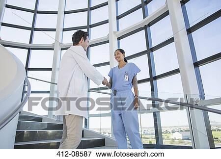 Stock Photo - Doctor and nurse handshaking on hospital staircase. Fotosearch