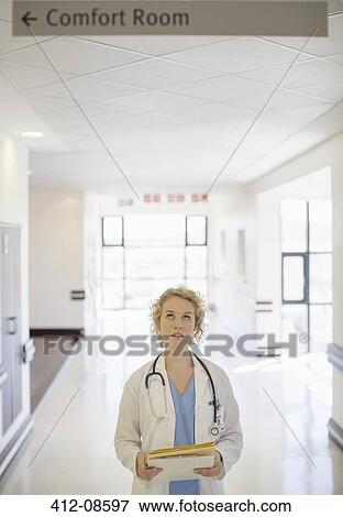 Doctor looking up at sign in hospital corridor View Large Photo Image Stock Photo - Doctor looking up at sign in hospital corridor. Fotosearch